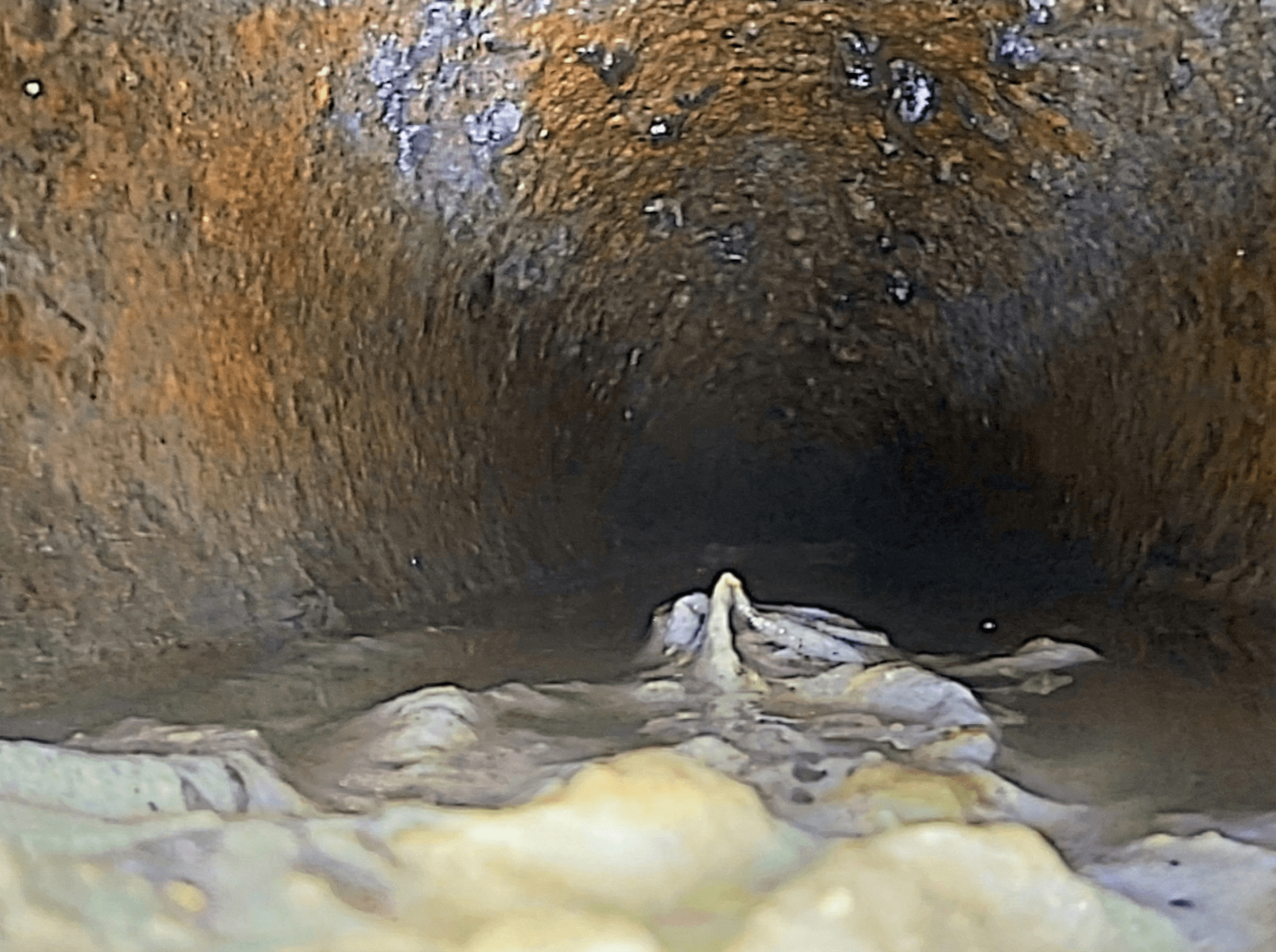 Rørinspeksjon med kamera som viser innsiden av et støpejernsrør med høyt vannnivå, rust og papir